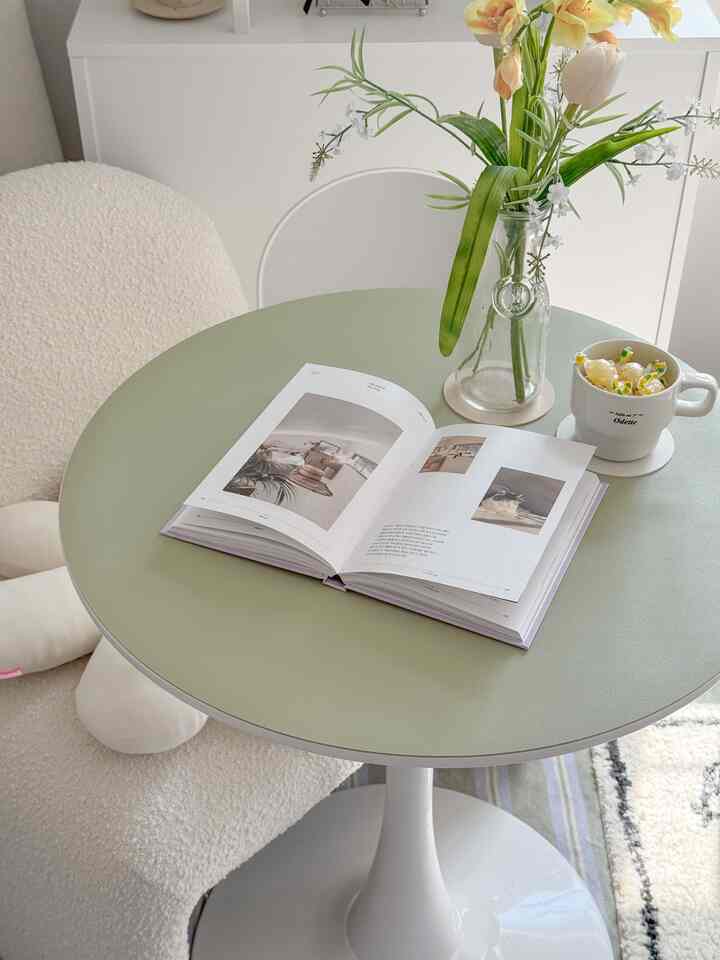 ナチュラルカラーの優しいオリーブグリーンの円形ダイニングテーブルとベージュのアームチェアが配置された雰囲気のあるナチュラルモダンなダイニング