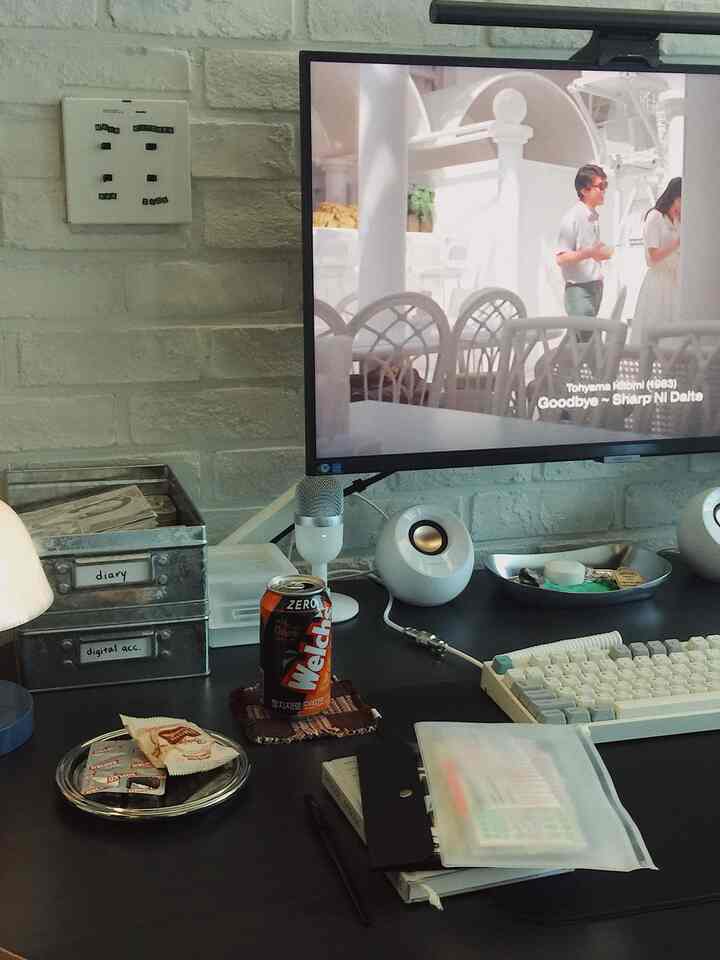 ホワイトとグレーのブリック壁を背景にしたコンパクトなミニマルホームオフィスデスク、モニターとトレイが配置された空間