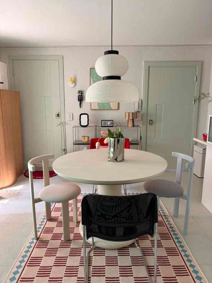 白とベージュのトーンのダイニングルーム、丸いダイニングテーブルとさまざまな椅子が配置されたモダンで落ち着いた空間