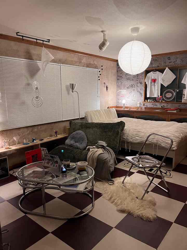 A warm wood-toned, vintage style cluttered studio apartment featuring sofa, bed, and pendant light with cozy atmosphere