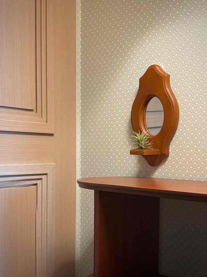 ナチュラルな木目調の玄関空間、小さな丸い鏡とキャビネットが配置された温かみのある雰囲気のインテリア