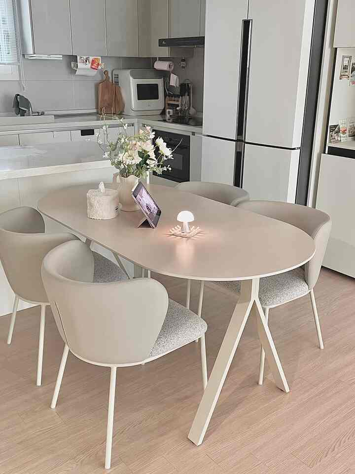 ホワイトとベージュの調和がとれたキッチン空間、ポーセリンセラミックのダイニングテーブルと4脚のジェナチェアが配された雰囲気のあるインテリア