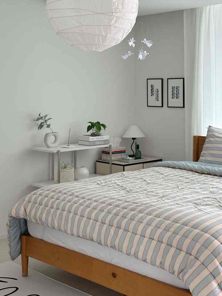 White and wood tone bedroom featuring striped bedding and small plants creating a cozy atmosphere