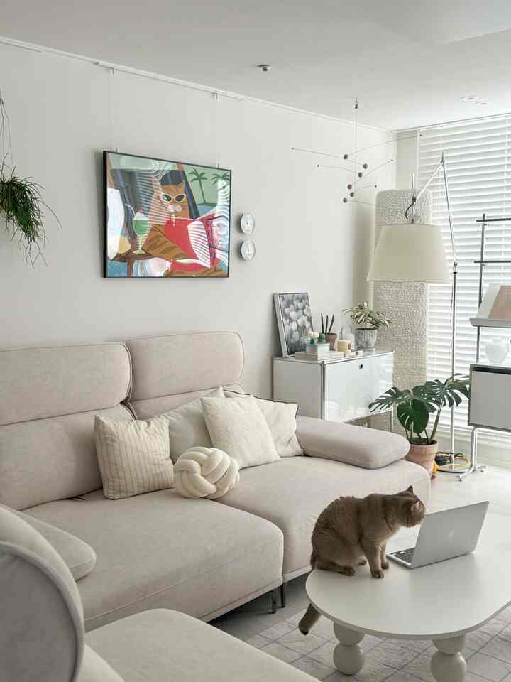 白とベージュのトーンのリビング、モダンなソファとコーヒーテーブルに猫が座る雰囲気のある空間