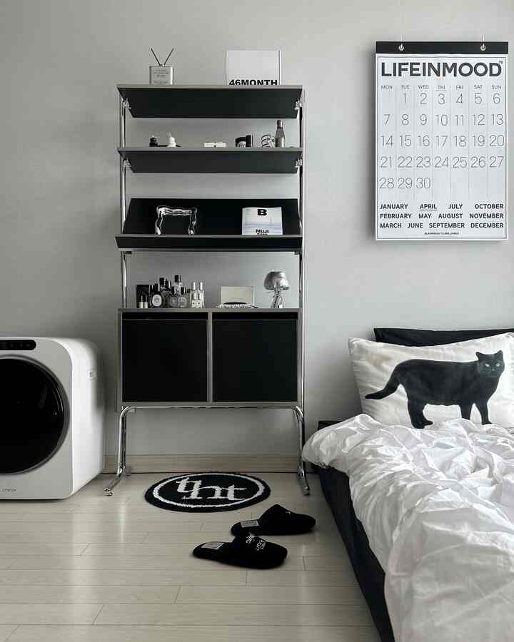 A modern bedroom featuring silver and black tones with a black cat pillow and sleek storage cabinet, creating a stylish atmosphere