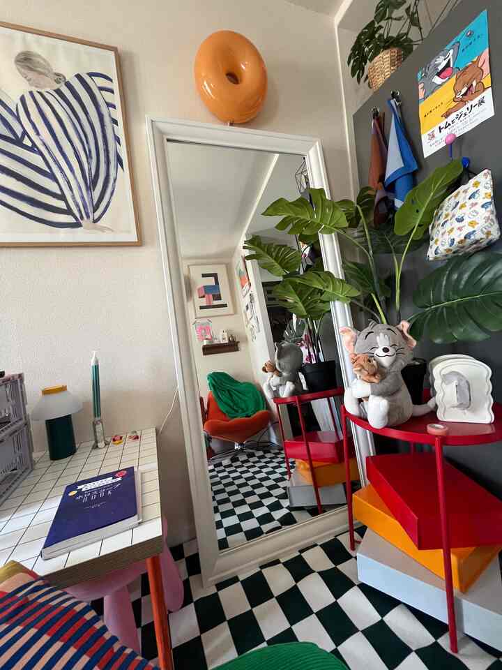 白と赤を基調としたミッドセンチュリーモダンの部屋、大きな鏡とサイドテーブル、チェッカードフロアが印象的な空間