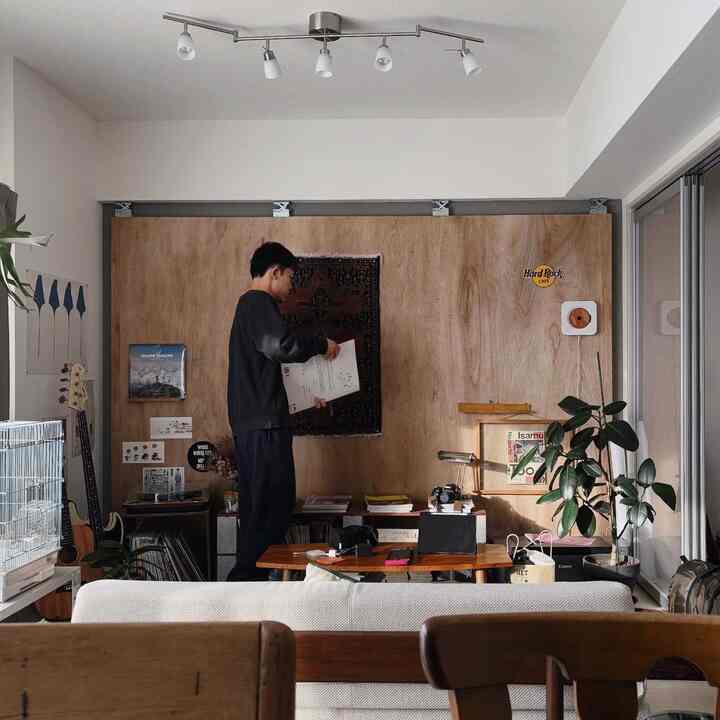 ナチュラルな木目調とヴィンテージ要素が調和するリビング、ソファと音楽関連のインテリアが印象的な落ち着いた空間