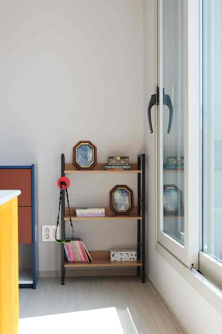 白い壁とナチュラルカラーのコーナー本棚、大きな窓が配置された清潔感のあるリビングスペース