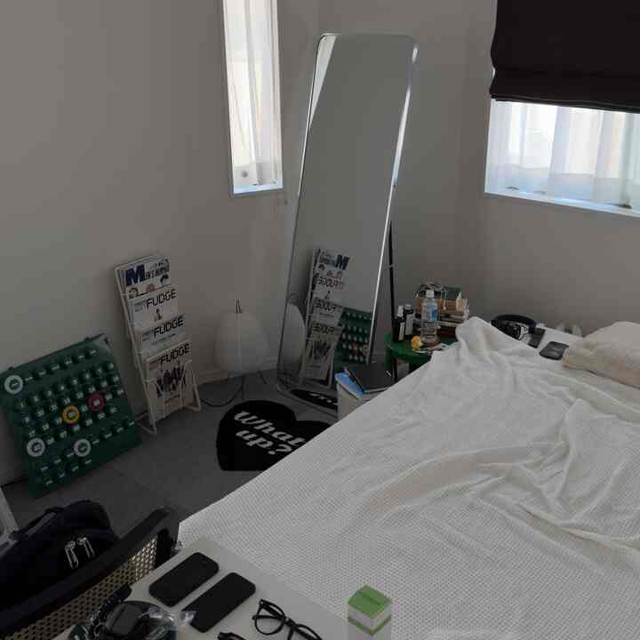 White and natural tone single household bedroom featuring a full-length mirror and small desk with a clean and practical atmosphere