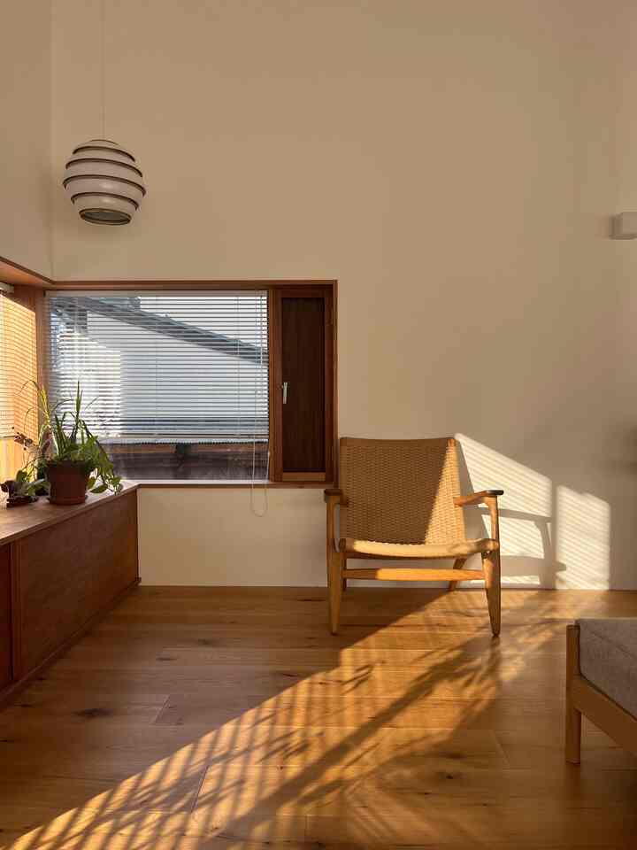 温かみのある木目調と自然光が調和する北欧とジャパンディスタイルのリビング、安らぐアームチェアとペンダントライトが配置された空間