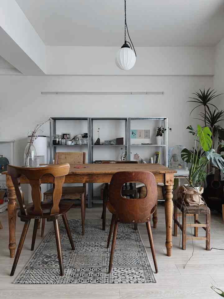 暖かいブラウンの木目調と白い壁のダイニング、ヴィンテージの食卓椅子と植物が配置された自然な雰囲気のインテリア