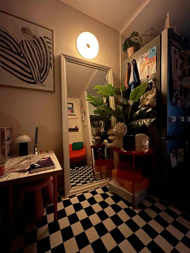 Cozy modern living room with black-and-white checkered floor, large mirror, and green plant by side table