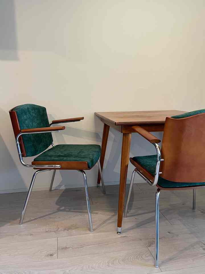 Natural-toned dining room featuring brown wood dining table and green fabric armchairs with a simple ambiance