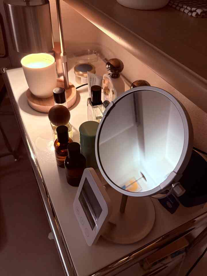 暖かい木目調と白色のモジュール家具の上にキャンドルと香水が配置された雰囲気のある化粧台空間