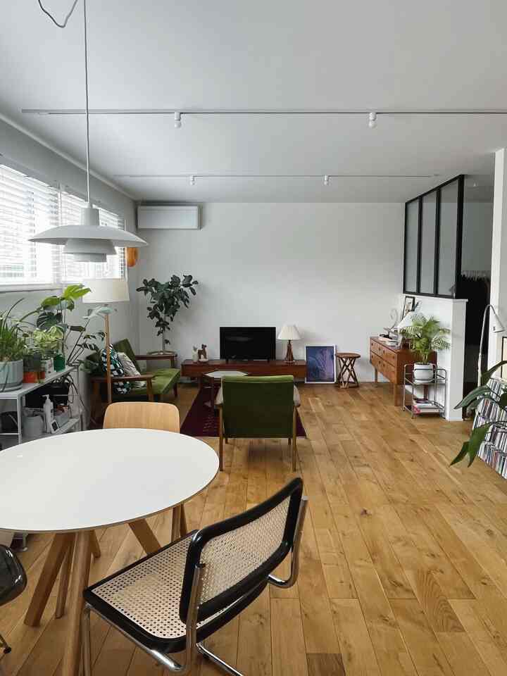 ナチュラルトーンのミッドセンチュリーモダンリビング、オリーブグリーンのソファと丸いダイニングテーブルが配置された落ち着いた空間