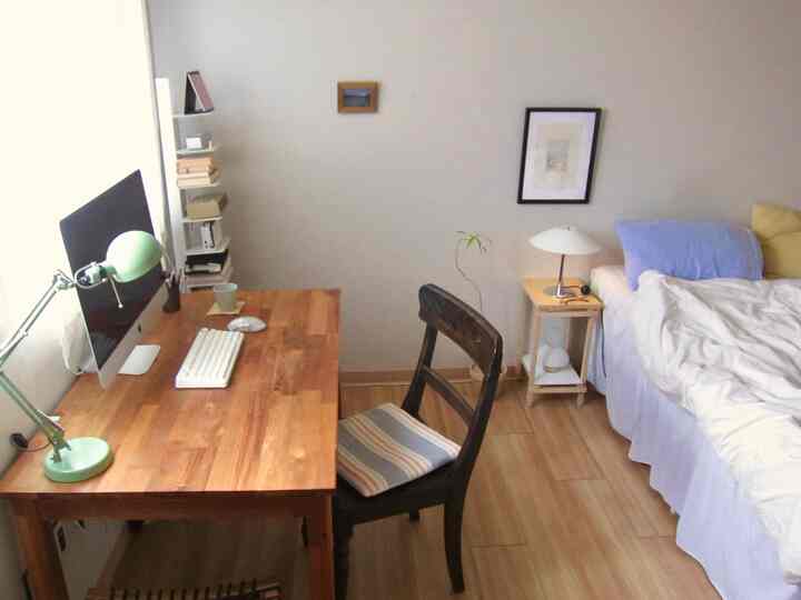 ナチュラルなウッドトーンとホワイトのワンルーム寝室、デスクとベッドが配置された雰囲気のあるインテリア