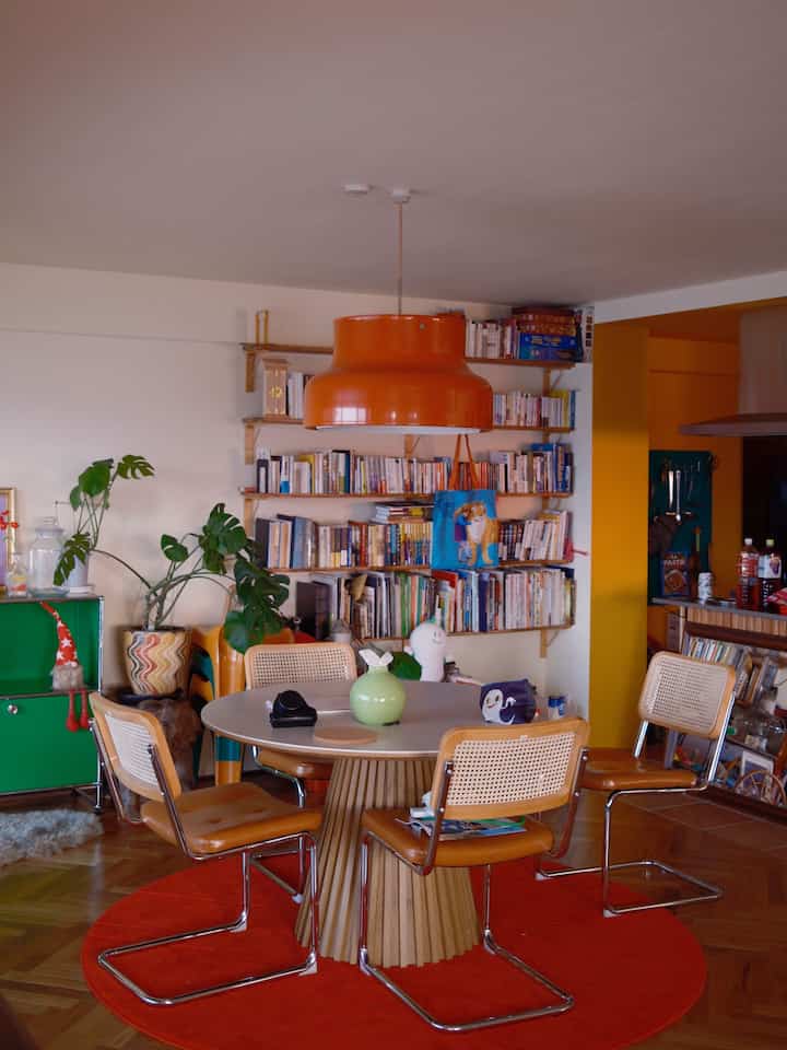 Orange and white tone living and dining room featuring a round table and pendant light with cozy vintage atmosphere