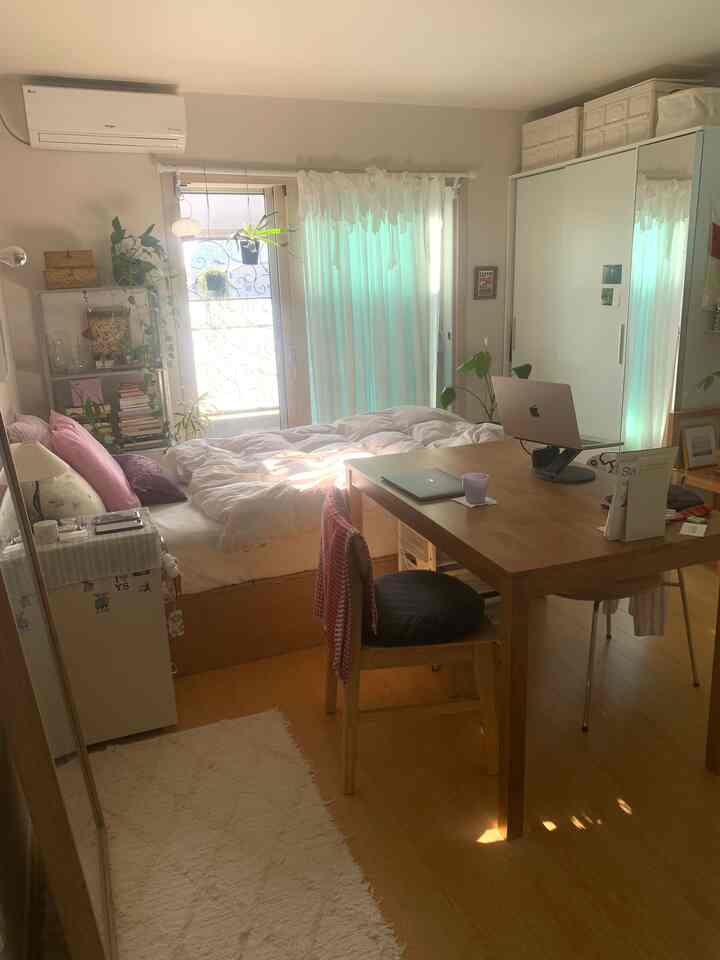 明るいホワイトと木目調の8坪ワンルーム、アットホームな寝室と多目的な木製ダイニングテーブルが配置された空間