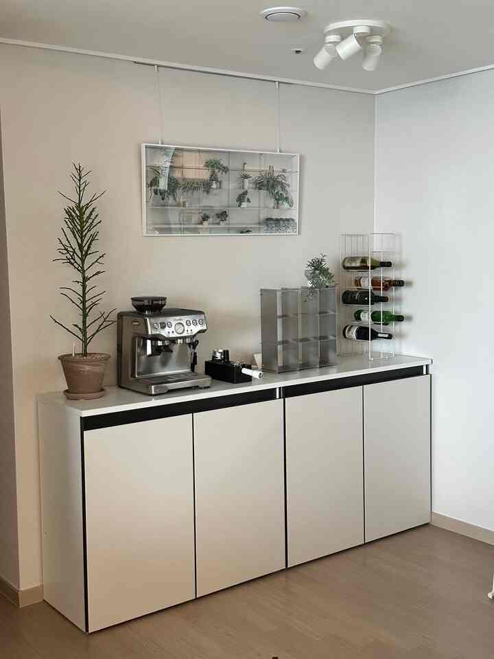 ホワイトと木目調の調和が美しいモダンなおうちカフェ、コーヒーマシンとワインラックが配置された整理された収納キャビネットの空間