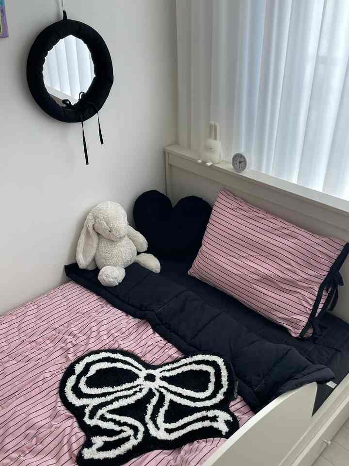 Pink and black toned children's bedroom featuring plush toy and cushions, creating a cozy atmosphere