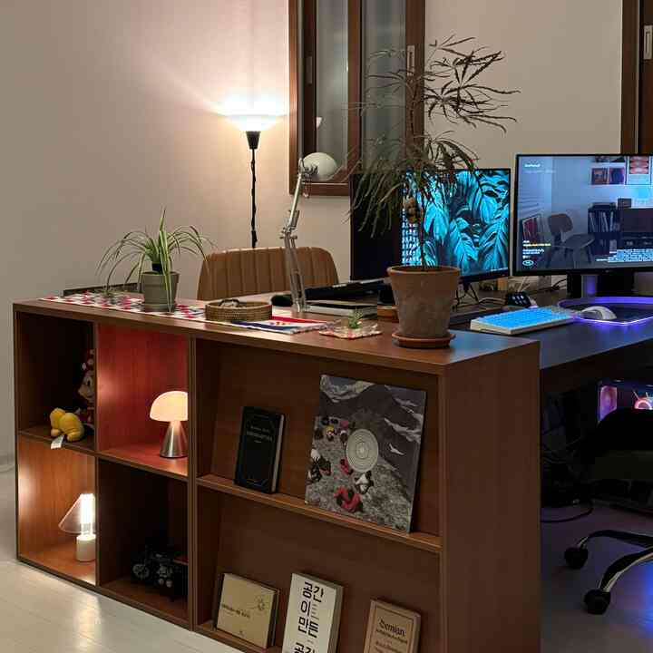 木目調と白を基調としたホームオフィス、デュアルモニターとデスク、棚、照明が配された落ち着いた作業空間