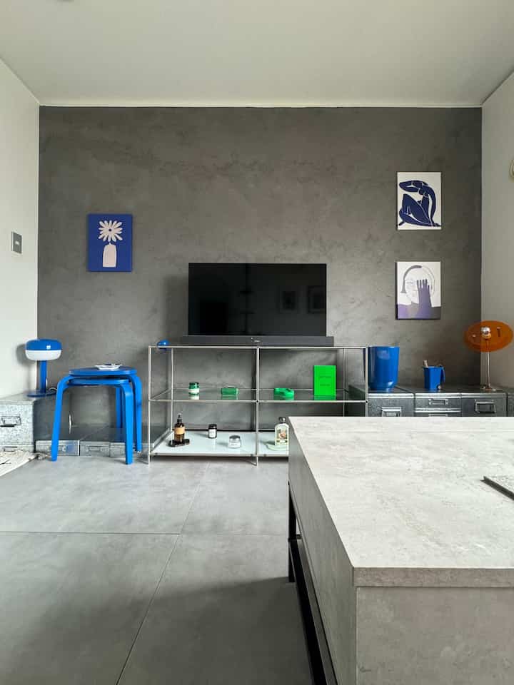 グレーの壁と床、ブルーの家具と小物が配置されたモダンなリビング