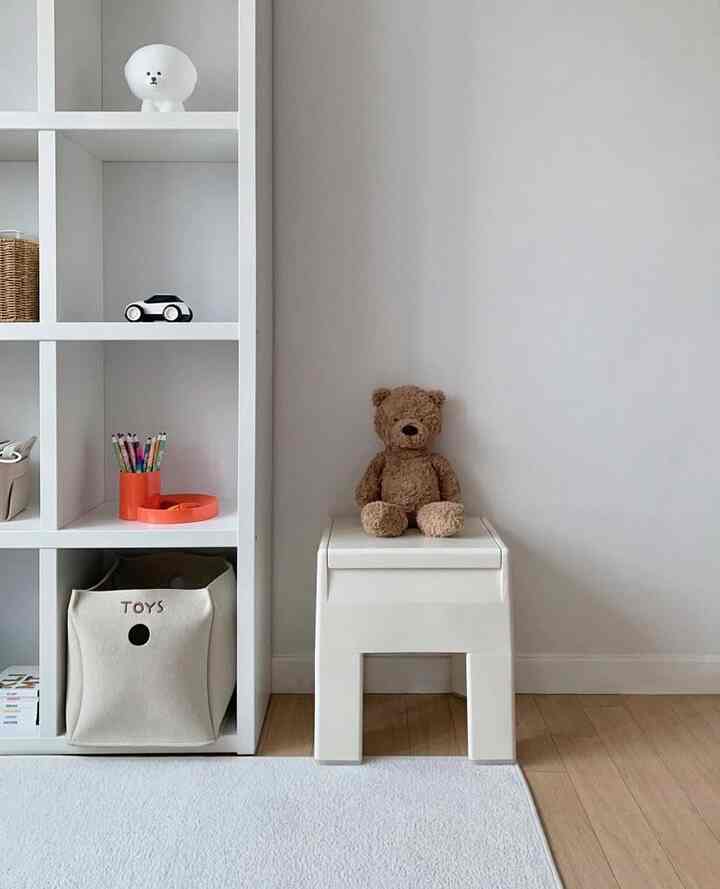 White and natural-toned kids' room featuring a storage stool and toy storage basket creating a cozy atmosphere