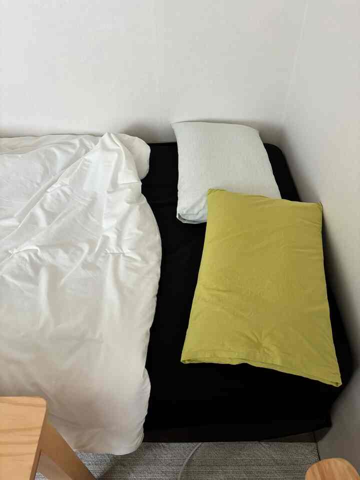 ホワイトとブラックのトーンの寝室、柔らかいマットレスと二つの枕が置かれたシンプルな空間