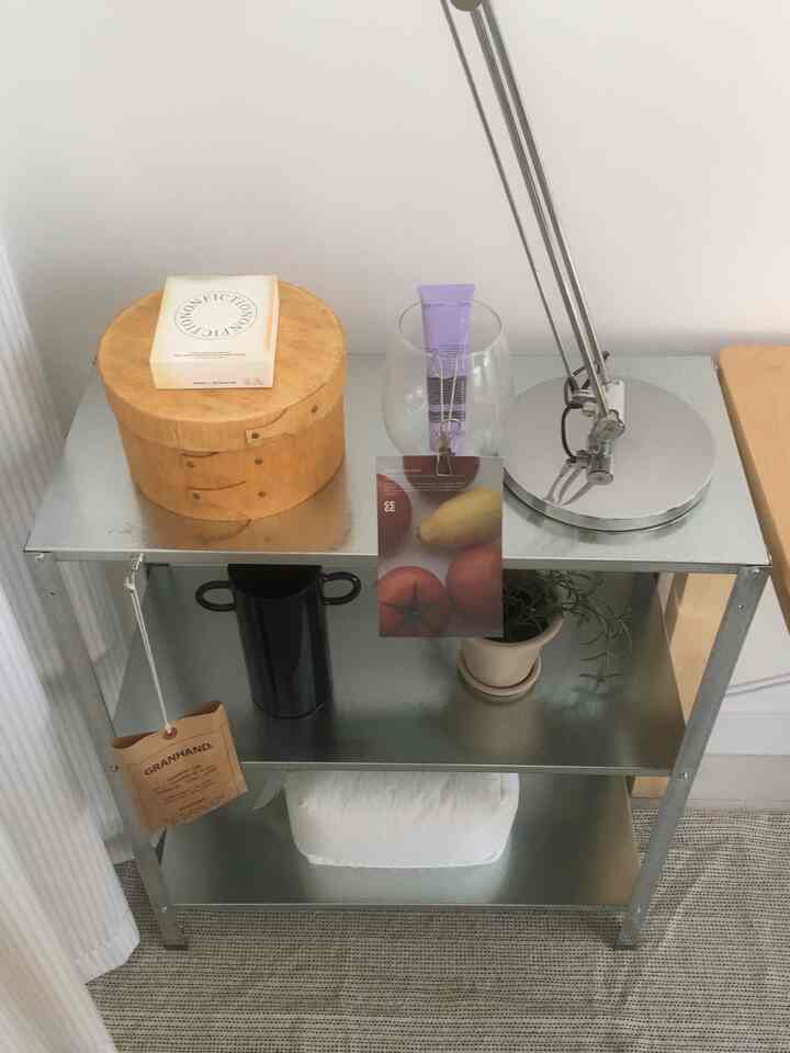 シルバーのメタルシェルフと木目調のボックスがあるミニマルなコンパクト空間、白いタオルと小さな植物が配置されたインテリア