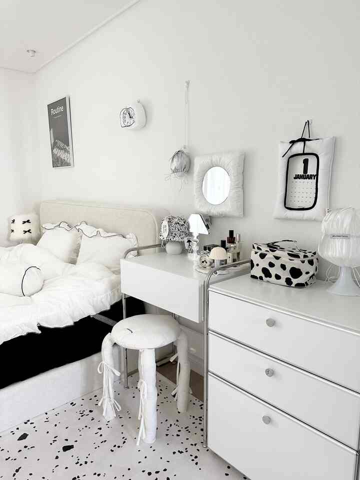 白と黒のモノトーンの寝室、クッションとスツールが配置された印象的なミッドセンチュリーモダンスタイルの空間