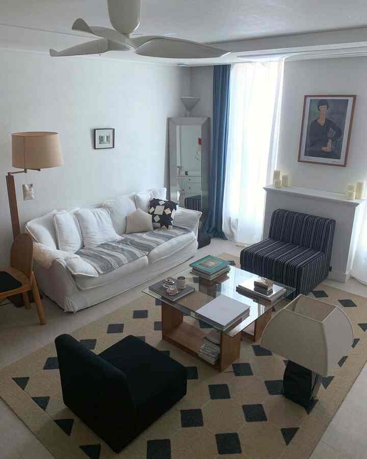 ホワイトとブラウンの色調のリビング、ソファとアームチェア、コーヒーテーブルが配置されたシンプルでヴィンテージ風の空間