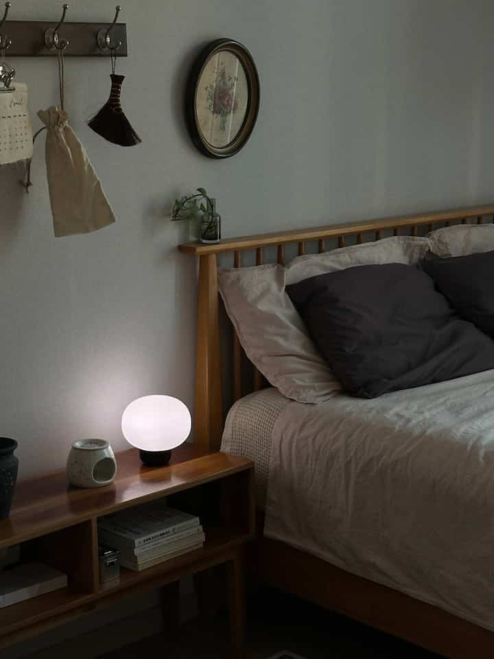 Beige and wood tone bedroom featuring a mid-century modern bed and a softly glowing table lamp creating a cozy atmosphere