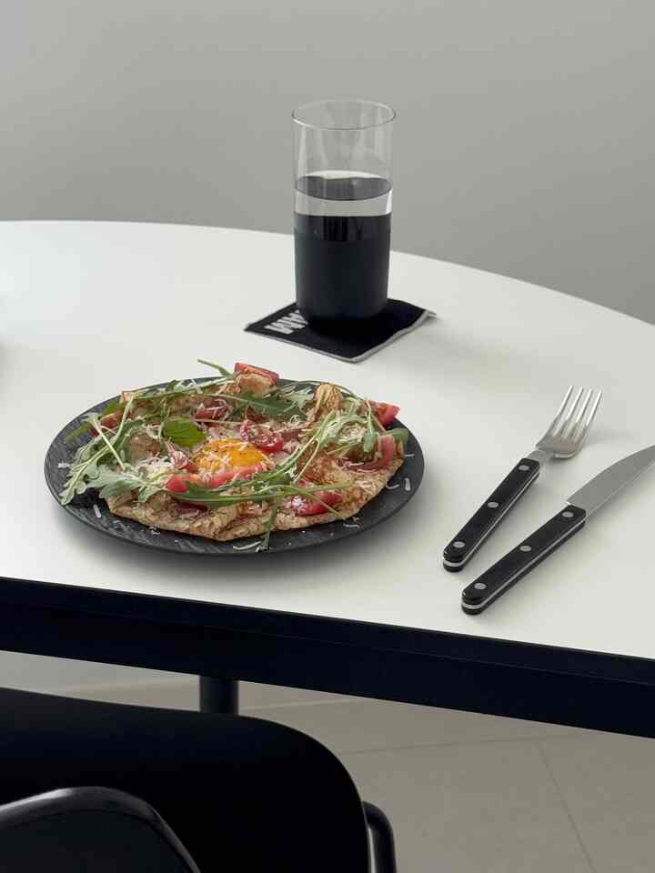 ホワイトのダイニングテーブルに黒い皿とカトラリーが配置されたシンプルで清潔感のあるダイニング空間