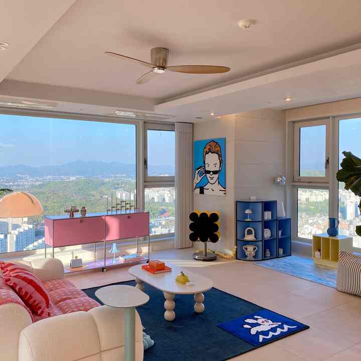 明るくモダンなリビングルーム、広い窓から青い絨毯と白いソファが調和した都市と山の眺望が見える印象的な空間