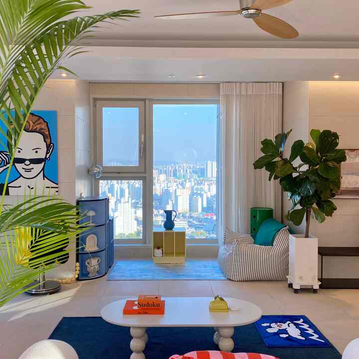 白と青の色調のリビング、ストライプのビーズクッションと植物が配置されたナチュラルな雰囲気のインテリア