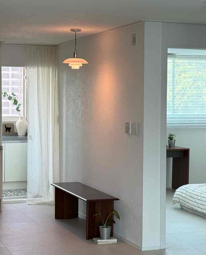 Minimal veranda space featuring white and wood tones, linen curtains, and a bench creating a natural and cozy atmosphere.