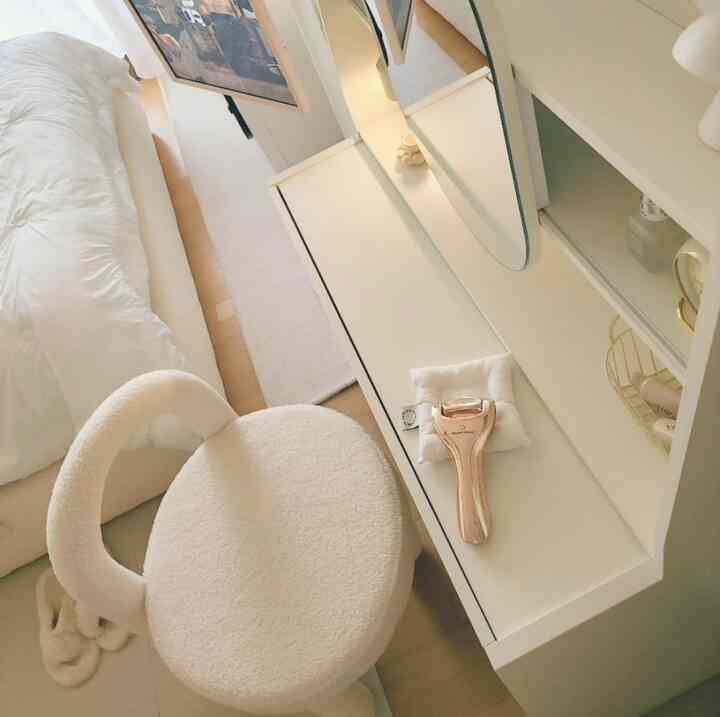 柔らかなホワイトトーンのワンルーム寝室、きれいなスライディングミラー化粧台と丸みのある椅子が配置されたミニマルなインテリア