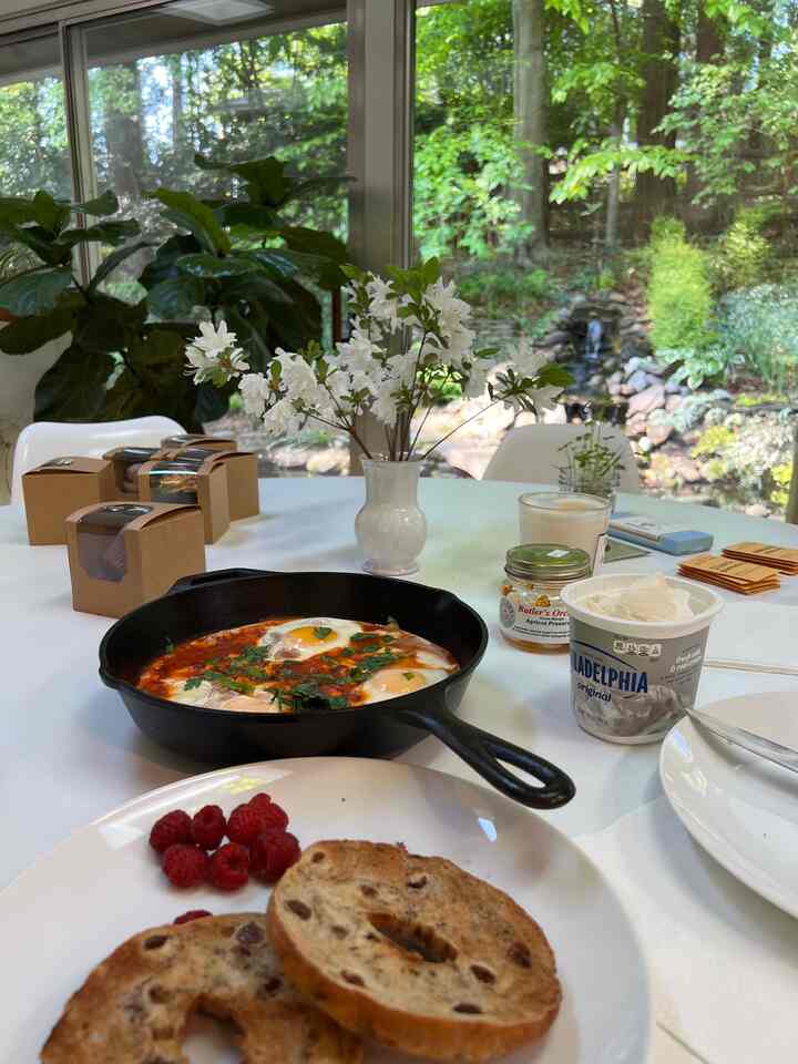 Bright white dining room with a dining table featuring a cast iron skillet with eggs, bagel, and green plants adding a natural vibe