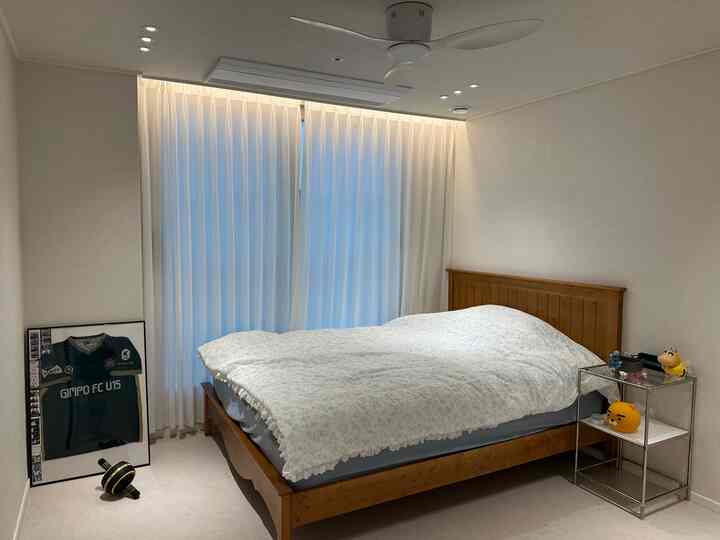 白とナチュラルウッドトーンの調和した小さな寝室、シンプルなベッドとナイトテーブルが配置された雰囲気のあるインテリア