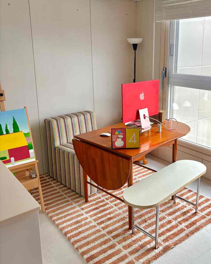 ナチュラルトーンのホームオフィス、木製デスクとストライプの椅子、ストライプのラグが配置された居心地の良いコンパクトな空間