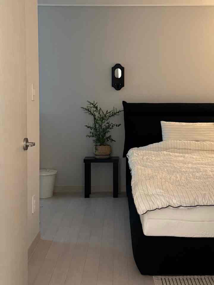 モダンな黒と白の寝室、ベッドと小さな収納兼化粧台が配置された雰囲気のあるインテリア