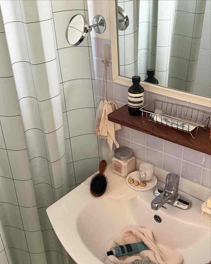 清潔感ある白いタイルと木目調の棚が配されたモダンなバスルームの洗面スペース