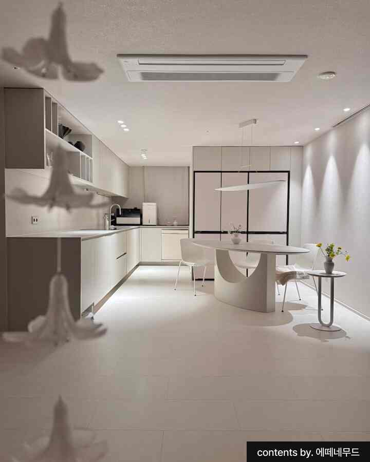 白を基調としたモダンなキッチンに円形のダイニングテーブルが配置されたシンプルで清潔感のある空間