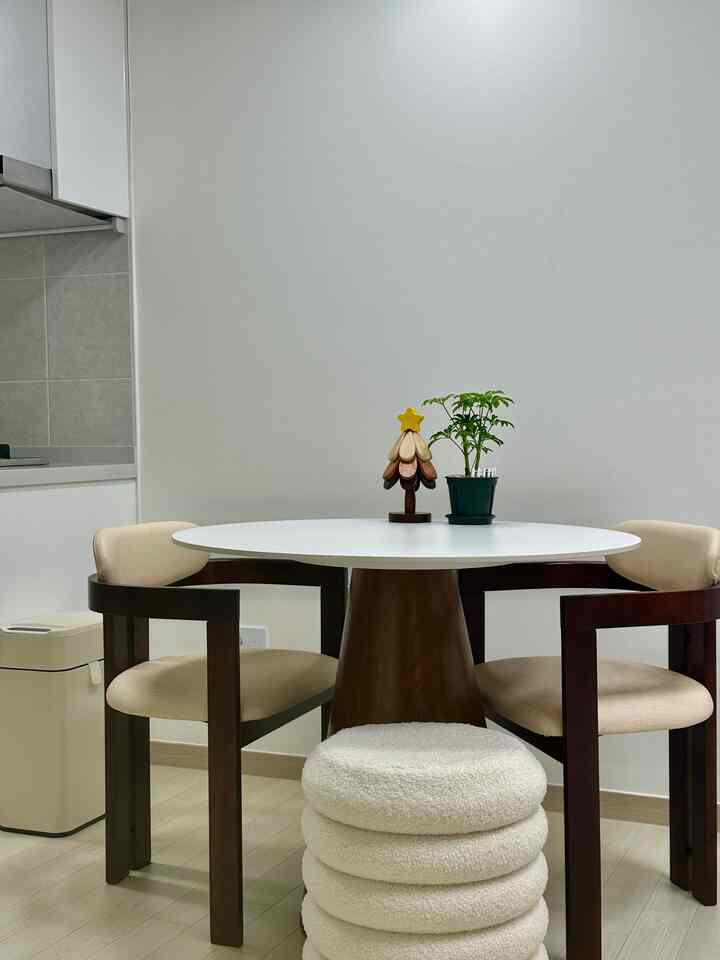 ナチュラルカラーと木目調が調和した2人用キッチンダイニング、円形の白いテーブルとベージュのダイニングチェアが配置されたシンプルな空間