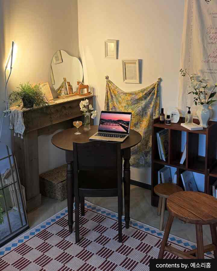 ベージュと木目調を基調としたナチュラルモダンなワンルームのホームオフィス空間。丸テーブルや鏡、植物が配置された落ち着いた雰囲気のインテリア