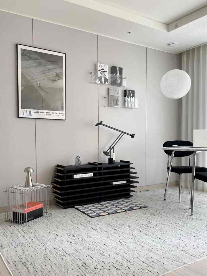 モノトーンのリビング、黒い家具と白いフロアランプ、明るいラグが配置されたシンプルモダンな印象的な空間