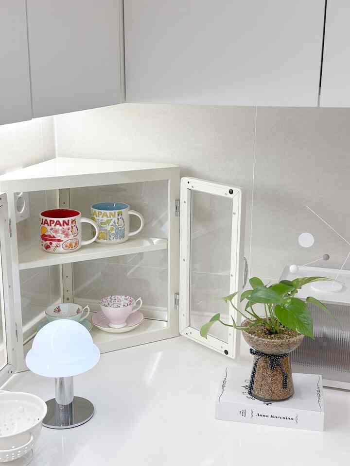 明るいホワイトトーンのキッチンコーナーキャビネットと植物が配置された、清潔感のあるモダンなインテリア