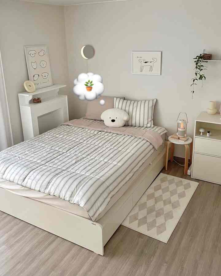 ナチュラルカラーとシンプルモダンの寝室、白とベージュのベッドとクッション、壁に犬のポスターが配置された温かみのあるインテリア