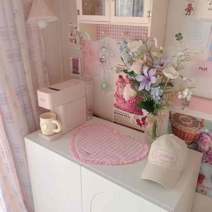 明るいホワイトとパステルピンクのトーンのワンルーム、アーチ型キャビネットの上にホームカフェ用品と花瓶が配置された温かみのあるインテリア