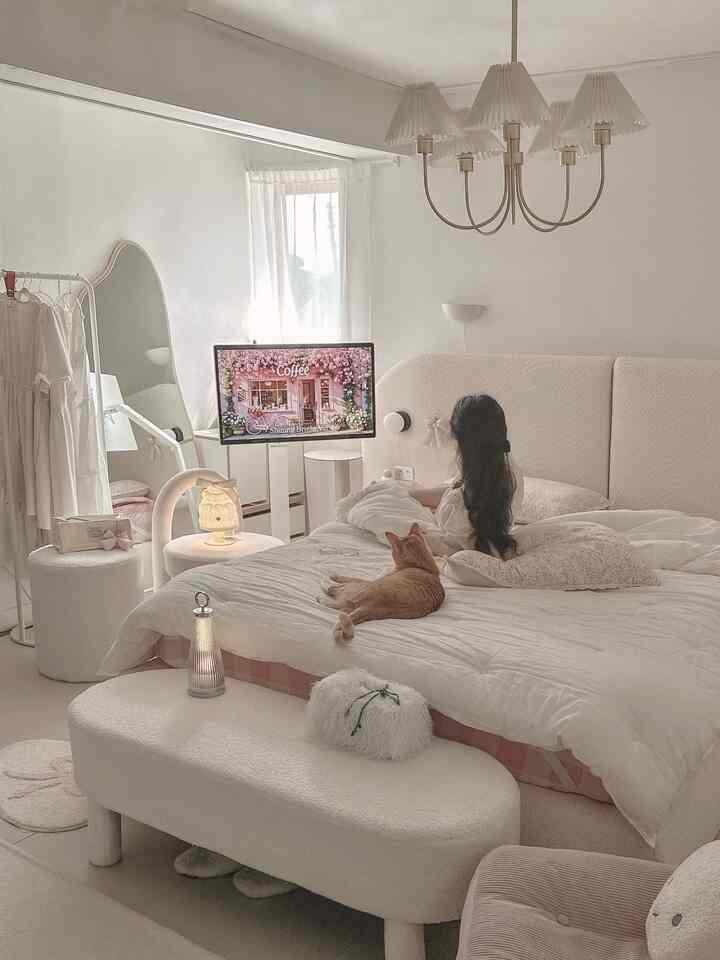 明るく柔らかなホワイトとベージュの寝室、中央に大きなベッドとくつろぐ猫がいるモダンでナチュラルな雰囲気のインテリア